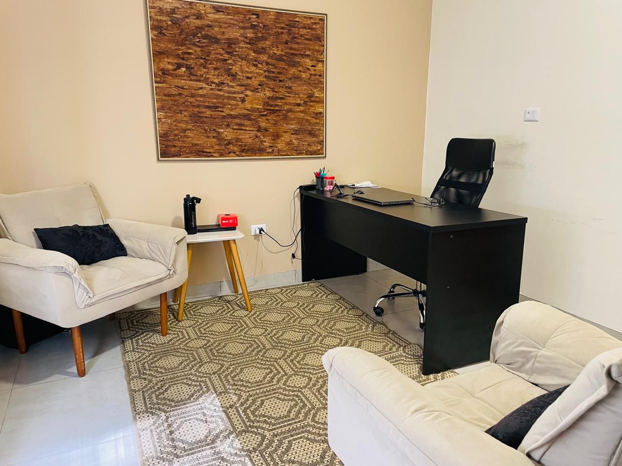 Sala com mesa preta, poltrona e painel de madeira