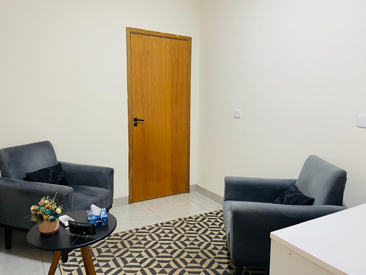 Sala com poltronas cinza e mesa lateral